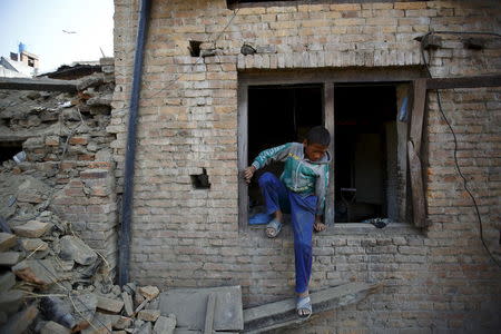 A boy exits from the window of his house as he works to clear debris, a month after the April 25 earthquake in Bhaktapur, Nepal May 25, 2015. REUTERS/Navesh Chitrakar
