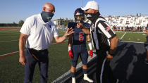 Herriman coach Dustin Pearce and Brock Hollingsworth (5) speak with an official during the coin toss before a high school football against Davis on Thursday, Aug. 13, 2020, in Herriman, Utah. Utah is among the states going forward with high school football this fall despite concerns about the ongoing COVID-19 pandemic that led other states and many college football conferences to postpone games in hopes of instead playing in the spring. (AP Photo/Rick Bowmer)