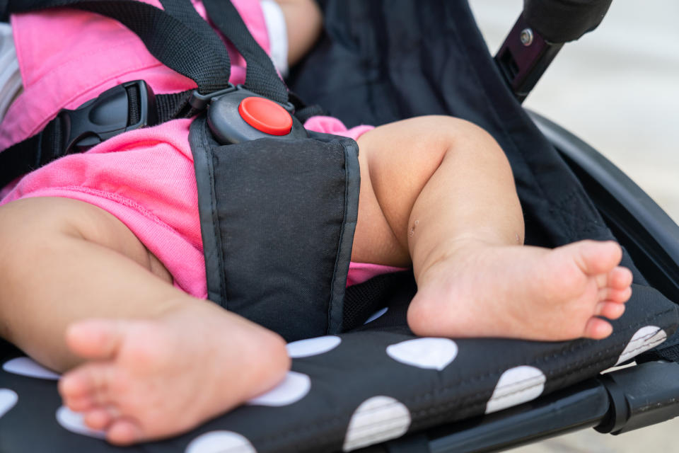 A close up a baby's feat and the safety harness on a pushchair