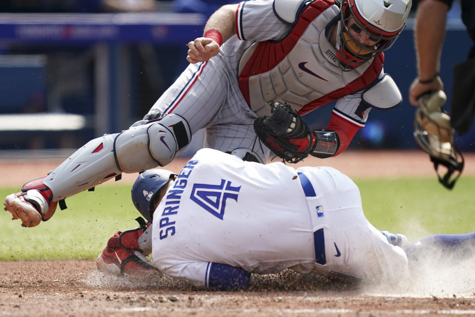 Toronto Blue Jays' George Springer (4) dives for home plate and collides with Minnesota Twins catcher Ryan Jeffers (27) during the fifth inning of a baseball game in Toronto, Saturday, June 10, 2023. Springer was safe on the play. (Arlyn McAdorey/The Canadian Press via AP)
