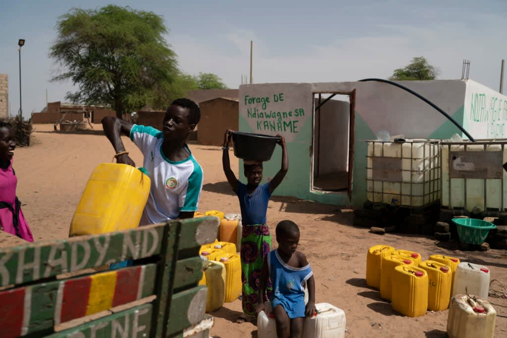 Three children handle water procured from a community well near their village of Ndiawagne Fall, which is located on one end of the Great Green Wall project. (AP Photo/Leo Correa, File)