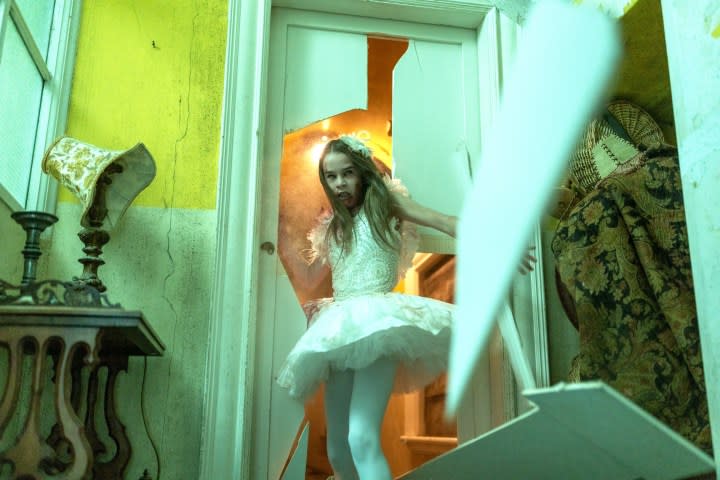 Alisha Weir charges through a door in Abigail.