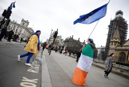 An anti-Brexit protester draped in an Irish tricolour flag and holding an EU flag stands outside of the Houses of Parliament in London, Britain, March 6, 2019. REUTERS/Toby Melville