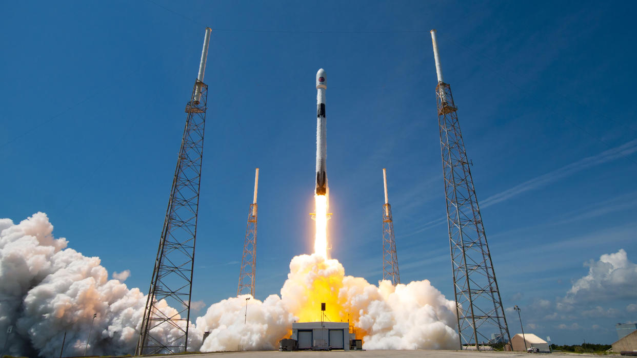  A SpaceX white and black rocket launches into a blue sky 