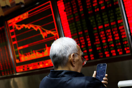 An investor sits in front of a board showing stock information at a brokerage office in Beijing, China, December 7, 2018. REUTERS/Thomas Peter/Files