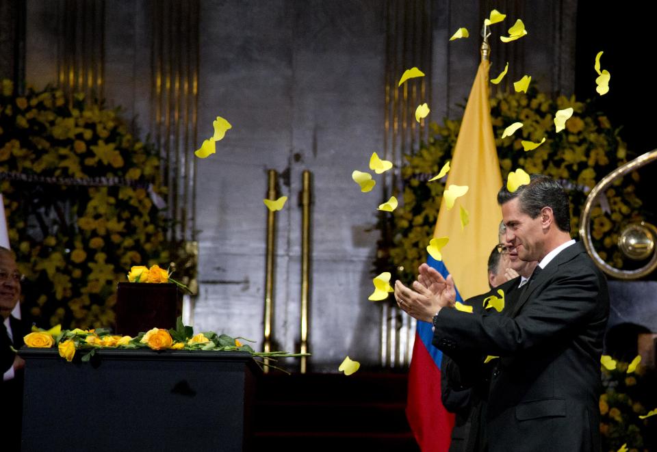 CORRECTS FALLING YELLOW OBJECTS ARE PAPER BUTTERFLIES - Yellow paper butterflies fall as Mexico's President Enrique Pena Nieto stands next to the urn containing the ashes of Colombian Nobel Literature laureate Gabriel Garcia Marquez during the authors homage at the Palace of Fine Arts in Mexico City, Monday, April 21, 2014. Garcia Marquez died on Thursday at his home in Mexico City. His magical realist novels and short stories exposed tens of millions of readers to Latin America's passion, superstition, violence and inequality. (AP Photo/Eduardo Verdugo)