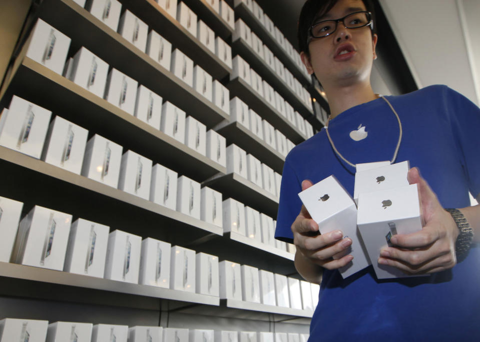 FILE-In this Friday, Sept. 21, 2012, file photo, a staff member of Apple Inc. shows the iPhone 5 to customers at the Apple store in Hong Kong. Apple Inc. said Monday Sept. 24 2012, that it has sold more than 5 million units of the new iPhone 5 in the three days since its launch, less than analysts had expected. (AP Photo/Kin Cheung, File)