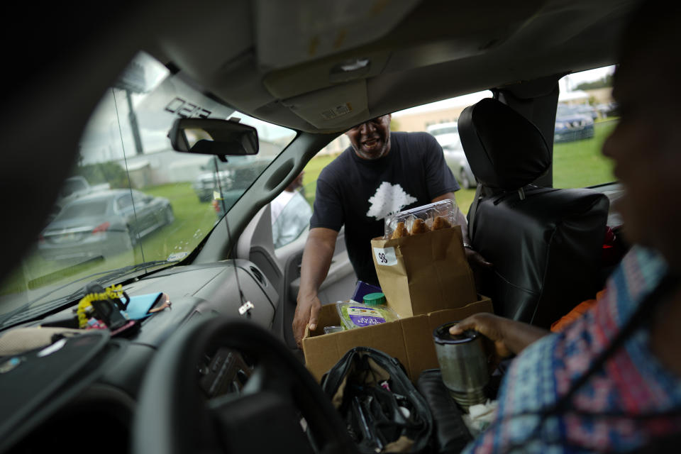 Church volunteer Abner Jackson Jr. places a box of donated groceries into the car of a visitor to the food pantry at The Life Center Church in Eatonville, Fla., Wednesday, Aug. 23, 2023. (AP Photo/Rebecca Blackwell)