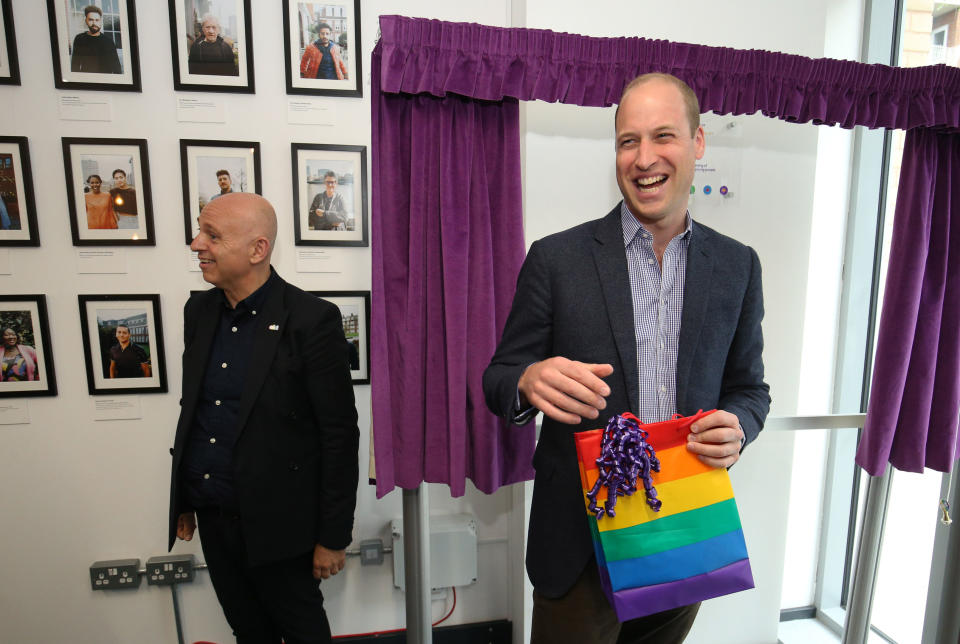 Prince William laughing while holding a multicoloured gift bag