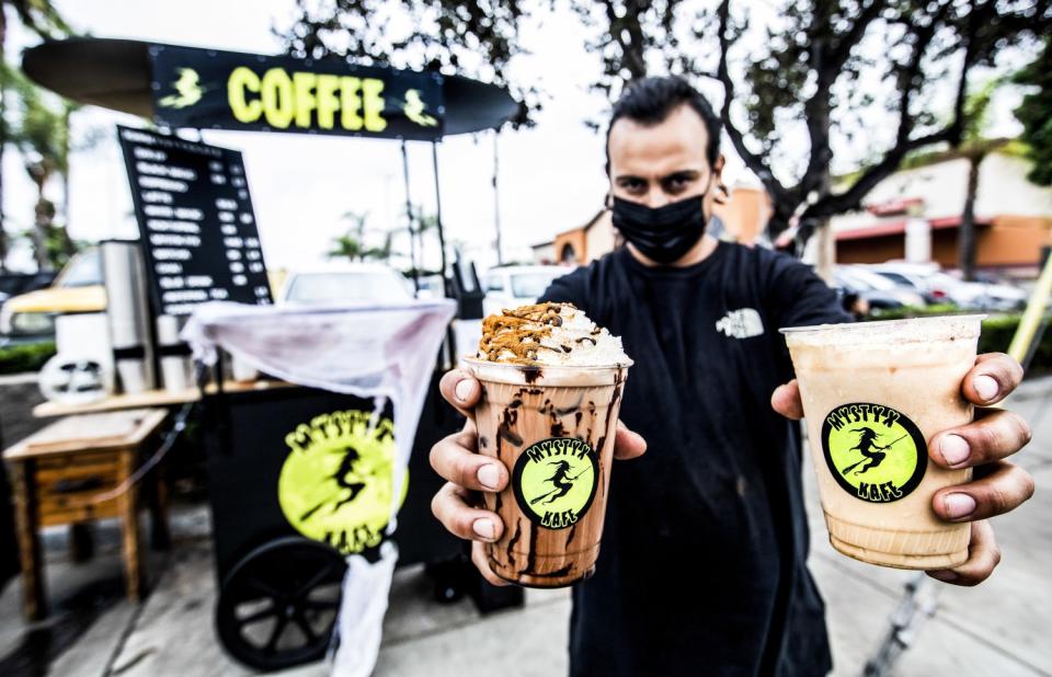 A man holds a coffee drink in each hand.