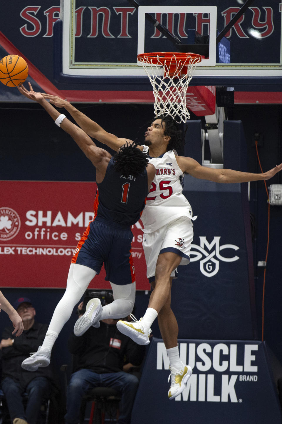 Pepperdine guard Michael Ajayi (1) attempts to shoot around the block of Saint Mary's forward Mason Forbes (25) during the first half of an NCAA college basketball game, Thursday, Feb. 15, 2024, in Moraga, Calif. (AP Photo/D. Ross Cameron)