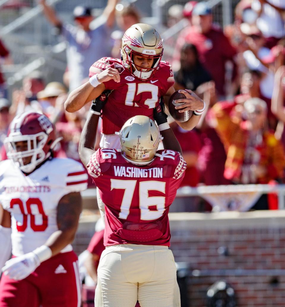 Florida State Seminoles quarterback Jordan Travis (13) is lifted up by Florida State Seminoles offensive lineman Darius Washington (76) after scoring a touchdown. The Florida State Seminoles leads the Massachusetts Minutemen 38-3 at the half Saturday, Oct. 23, 2021.