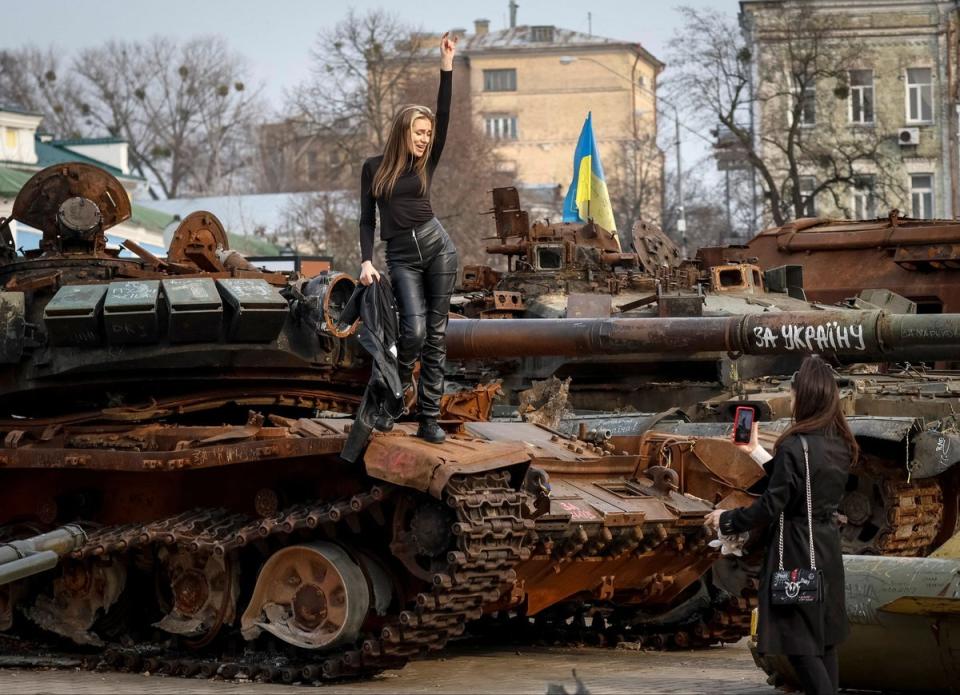 Women take a picture atop a destroyed Russian tank during an exhibition displaying destroyed Russian military vehicles in Kyiv (REUTERS)