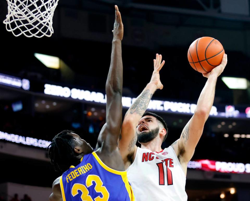 N.C. State’s Dusan Mahorcic is fouled as he drives against Pitt’s Federiko Federiko during the second half of a men’s basketball game at PNC Arena on Friday, Dec. 2, 2022, in Raleigh, N.C.