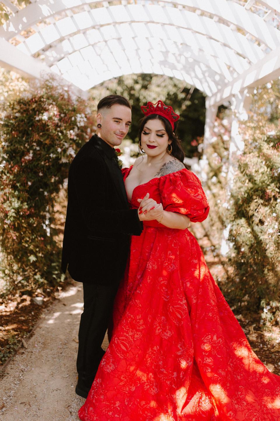 A man in a black suit and a woman in a red dress dance together.