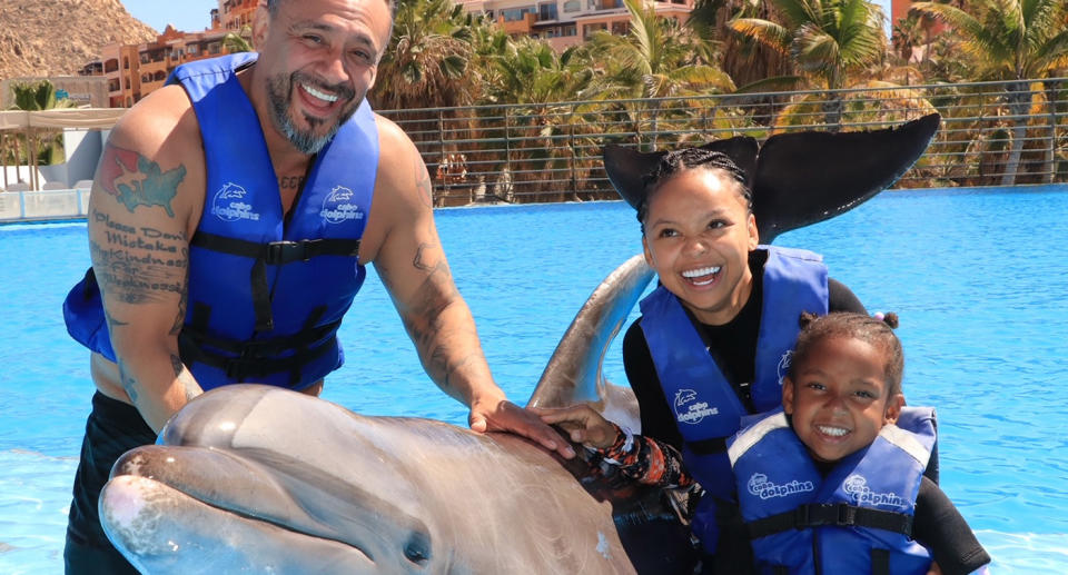 Age gap couple and daughter with dolphin at marine wildlife park