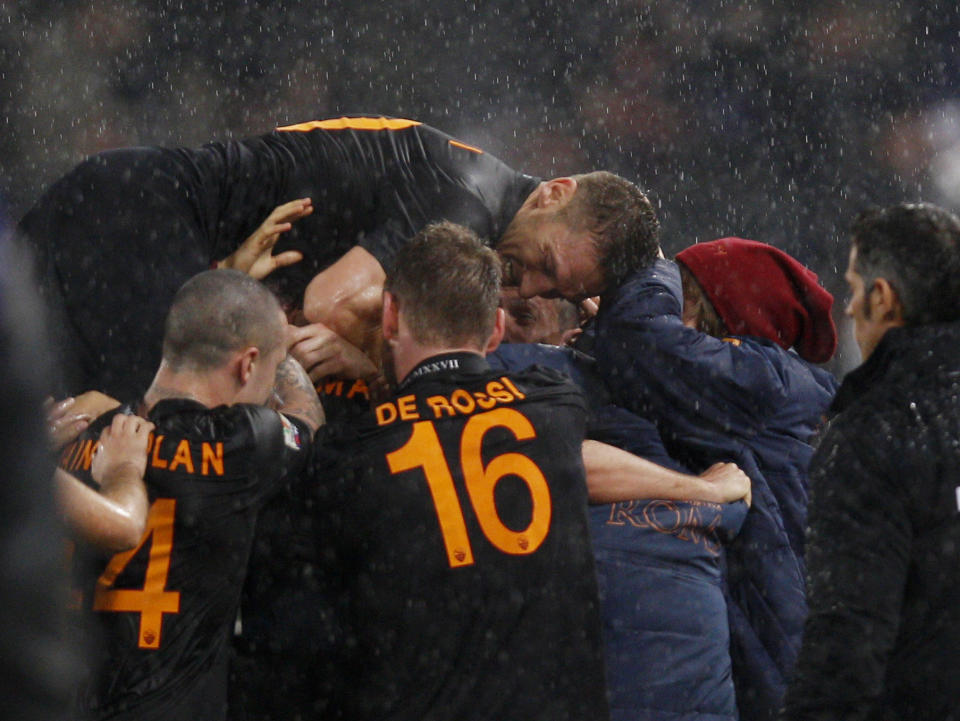 AS Roma forward Francesco Totti jumps on his teammates celebrating AS Roma midfielder Kevin Strootman, covered at center, after he scored during an Italian Cup, semifinal first leg match, between AS Roma and Napoli at Rome's Olympic stadium, Wednesday, Feb. 5, 2014. (AP Photo/Alessandra Tarantino)