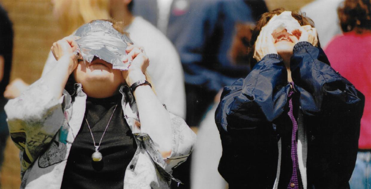 Elaine Fobean, left, watches a solar eclipse through a Pop-Tart wrapper May 10, 1994, while her friend Kathryne Mihelick uses Ho-Ho wrappers. Fobean’s son, Rick, a technical drafter, told the Stow women the method was safe.