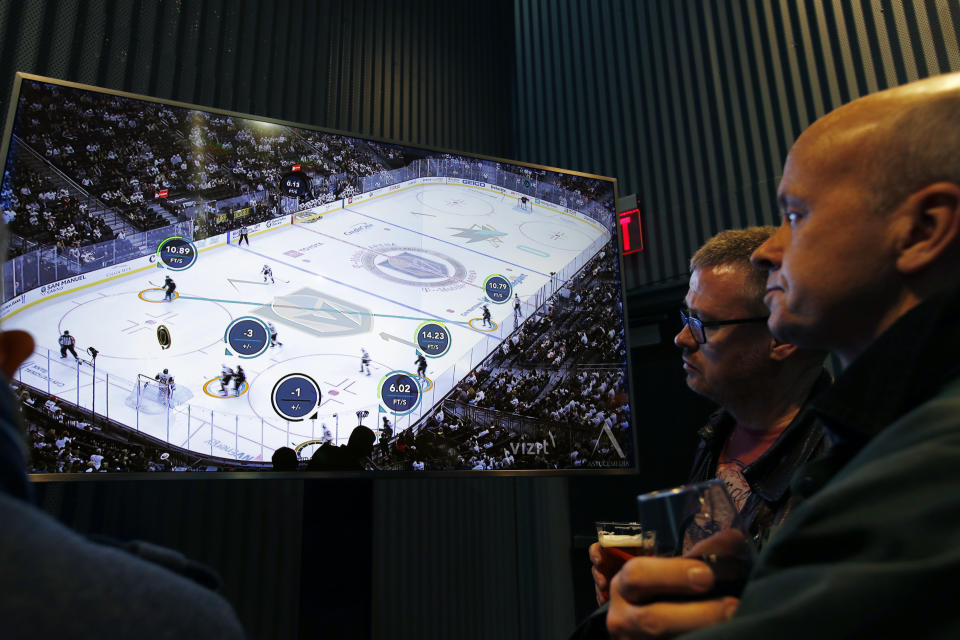 People watch real-time puck and player tracking technology on display during an NHL hockey game between the Vegas Golden Knights and the San Jose Sharks, in Las Vegas, Thursday, Jan. 10, 2019. The NHL for the first time has tested real-time puck and player tracking in regular-season games with the aim of having it ready for the 2019-20 season. Microchips were added to players’ shoulder pads and fitted inside specially designed pucks for two Vegas Golden Knights home games this week: Tuesday against the New York Rangers and Thursday against the San Jose Sharks. Antennas stationed around the arena tracked the players and the puck through radio frequencies and beamed the data to a suite where league and Players’ Association executives and representatives from 20 teams and various technology firms, sports betting companies and TV rights holders were on hand for the two nights of testing.(AP Photo/John Locher)