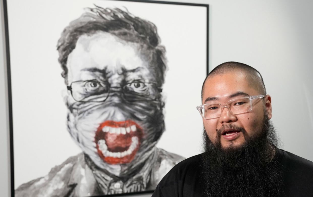 Chinese dissident artist Badiucao speaks as he stands in front of his works ahead of the opening of a new exhibition in Warsaw