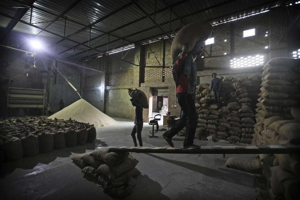 FILE- Laborers stack rice in a private warehouse in Makhu, in the Indian state of Punjab, March 12, 2021. Countries worldwide are scrambling to secure rice after a partial ban on exports by India cut supplies by roughly a fifth. Even before India’s restrictions, countries already were frantically buying rice in anticipation of scarcity later when the El Nino hit, creating a supply crunch and spiking prices. (AP Photo/Manish Swarup, File)