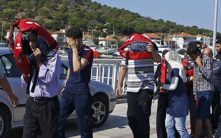 Syrian migrants cover their faces after being brought to the shore by the Turkish coast guards in Cesme, near the Aegean port city of Izmir, Turkey, August 11, 2015. REUTERS/Osman Orsal