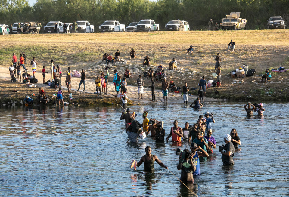 U.S. Border Patrol agents watch from their vehicles as migrants cross from a camp in Del Rio, Texas to go get food supplies on September 22, 2021 as seen from Ciudad Acuna, Mexico. U.S. immigration authorities have been deporting planeloads of migrants directly to Haiti, and others are reportedly being released into the United States to follow their asylum claims.  (John Moore/Getty Images)