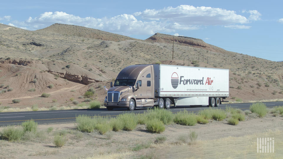 A sleeper cab pulling a white Forward Air dry van trailer