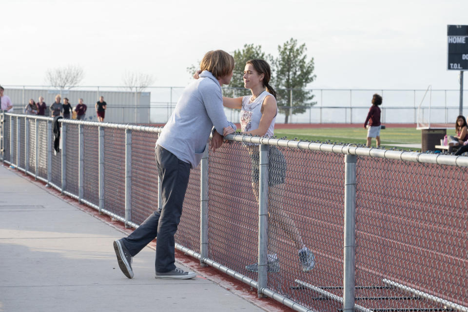 couple touching and talking to each other over a fence by the track field