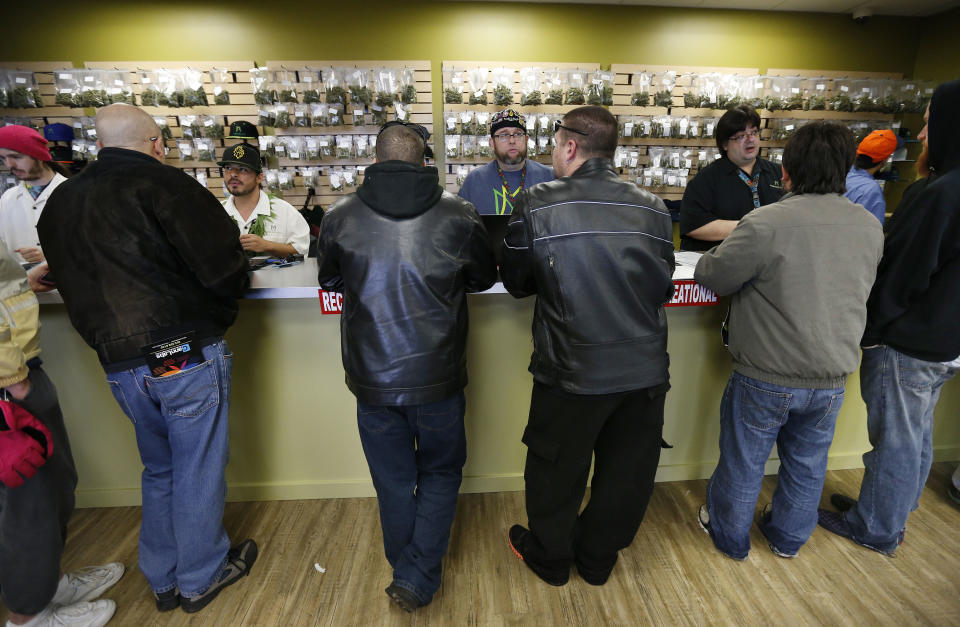 FILE - In this Jan. 1, 2014 file photo, employees help customers at the crowded sales counter inside the Medicine Man marijuana retail store, in Denver. A group of marijuana activists want another pot vote in Colorado, to loosen restrictions on who can have it. A proposed ballot measure up for state review Wednesday Jan. 14, 2014 would end criminal penalties for cannabis possession. If approved, the measure would effectively discard Colorado’s 1-ounce possession limit and 21-and-over restriction. (AP Photo/Brennan Linsley, File)