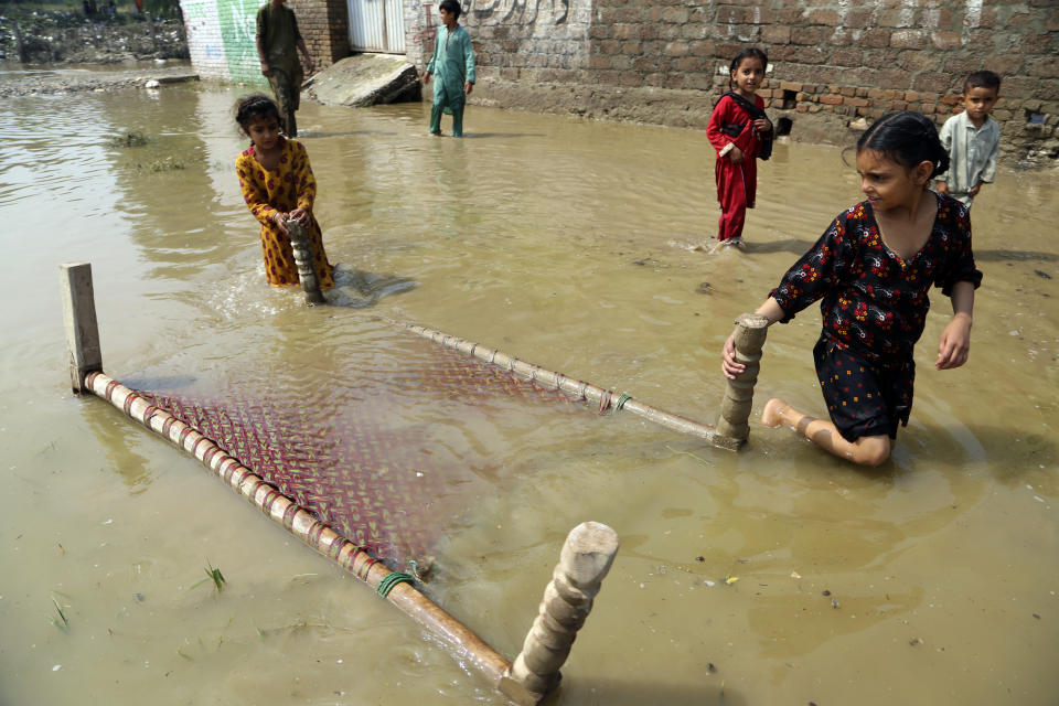 Children salvage a cot from their flood-hit home, in Charsadda, Pakistan, Wednesday, Aug. 31, 2022. Officials in Pakistan raised concerns Wednesday over the spread of waterborne diseases among thousands of flood victims as flood waters from powerful monsoon rains began to recede in many parts of the country. (AP Photo/Mohammad Sajjad)