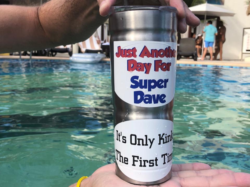 hands holding up a personalized tumbler cup in a pool