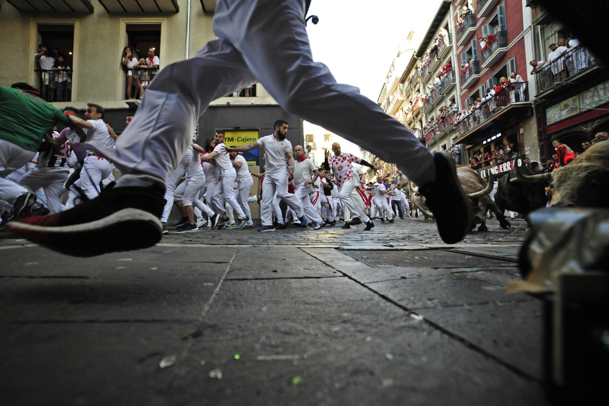 People run through the streets with fighting bulls and steers during the first day of the running of the bulls at the San Fermin Festival in Pamplona, northern Spain, Thursday, July 7, 2022. Revelers from around the world flock to Pamplona every year for nine days of uninterrupted partying in Pamplona's famed running of the bulls festival which was suspended for the past two years because of the coronavirus pandemic. (AP Photo/Alvaro Barrientos)