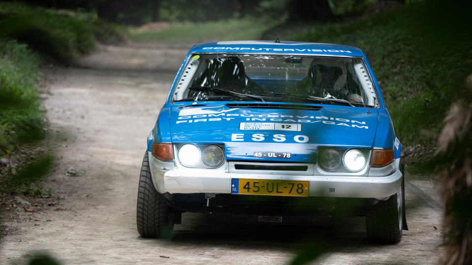 A rally car turning the corner of a race track at Goodwood