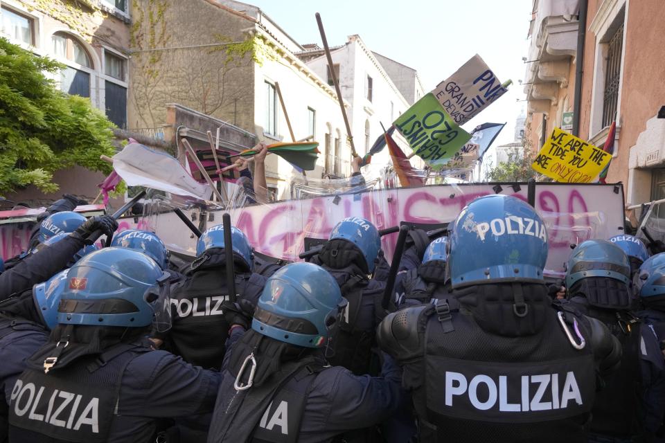 Demonstrators push their placards against a line of Italian Policemen in riot gears during a protest against the G20 Economy and Finance ministers and Central bank governors' meeting in Venice, Italy, Saturday, July 10, 2021. (AP Photo/Luca Bruno)