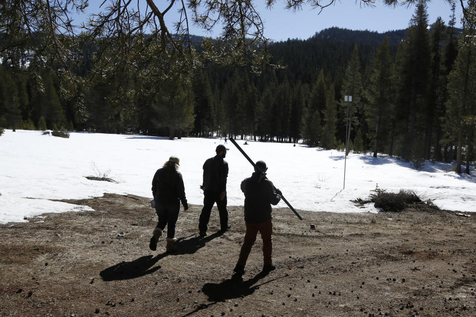 Sean de Guzman, chief of snow surveys, for the California Department of Water Resources, right, carries the snowpack measuring tube as he and DWR's Chief of State Water Project Operations Molly White, left, and Water Resources Engineer Nathan Burley, center, cross an area normally covered in snow during the third snow survey of the season at Phillips Station near Echo Summit, Calif., Thursday, Feb. 27, 2020. The survey found the snowpack at 29 inches deep with a water content of 11.5 inches at this location. (AP Photo/Rich Pedroncelli)