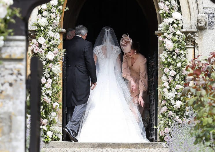 The Duchess of Cambridge adjusts PIppa’s train and veil as the bride walks into St Mark’s church [Photo: PA]