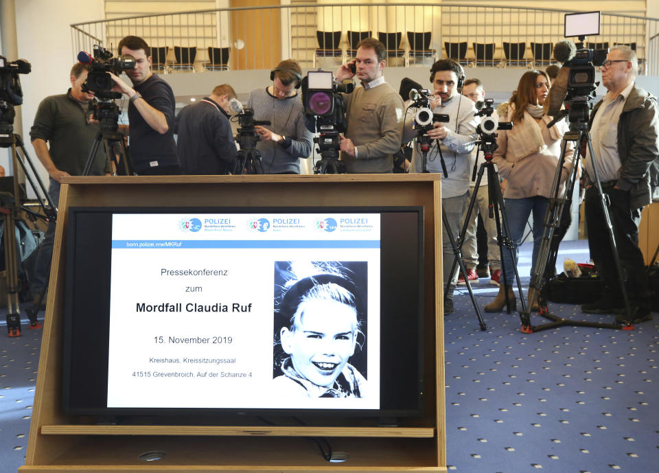 In this Friday, Nov. 15, 2019 photo a picture of Claudia Ruf is seen on a video screen as jounalists wait for the start of a press conference in Grevenbroich, Germany. Police in the western German city of Grevenbroich have asked about 900 men to come forward and have their DNA tested to help solve the gruesome killing of an 11-year-old girl decades ago. The girl, Claudia Ruf, was kidnapped, raped and choked to death by an anonymous murderer in 1996. (Roland Weihrauch/dpa via AP)