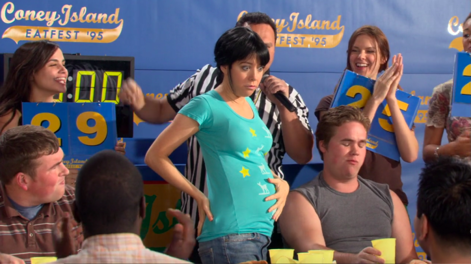 Lily holding her stomach after an eating contest in "How I Met Your Mother"