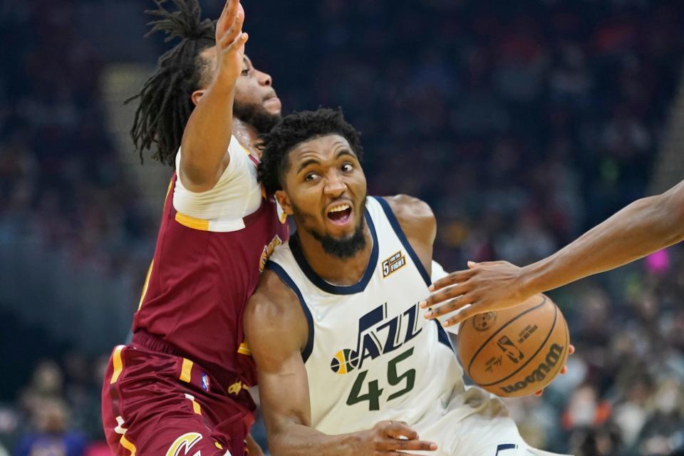 Utah Jazz's Donovan Mitchell (45) drives against Cleveland Cavaliers' Darius Garland, left, in the first half of an NBA basketball game, Sunday, Dec. 5, 2021, in Cleveland. (AP Photo/Tony Dejak)