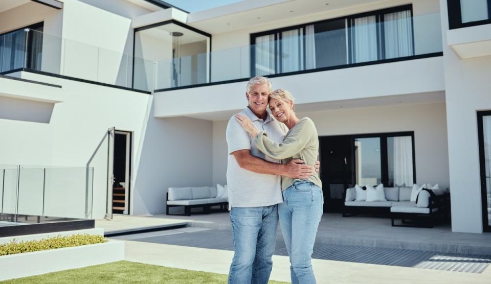 happy older couple smiling in front of their newly purchased home