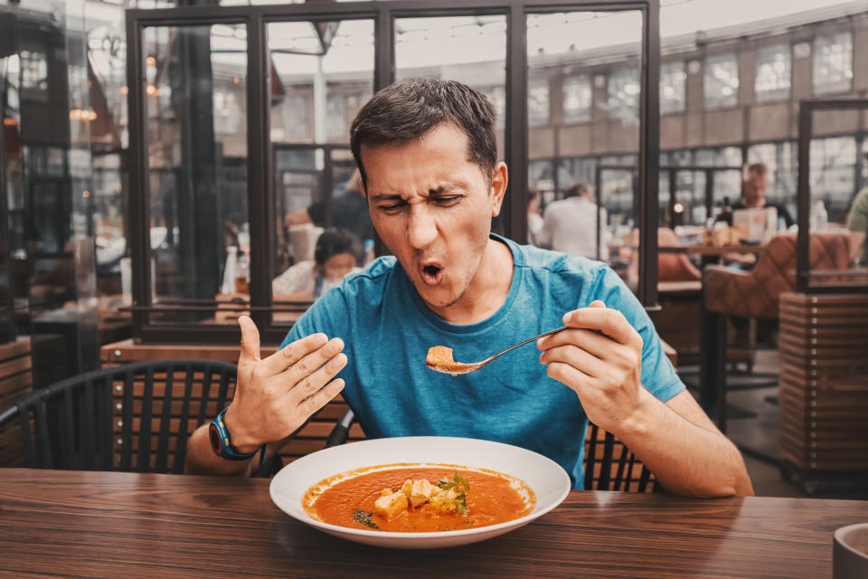 A man tries a spicy red soup in a restaurant and reacts strangely emotionally. Spices in the national cuisine and an unhealthy diet with too much pepper