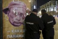 Russian police officers stand near a poster depicting Russian President Vladimir Putin and reading "Which Panama?" at a bus stop in Moscow, Russia, April 6, 2016. REUTERS/Sergei Karpukhin