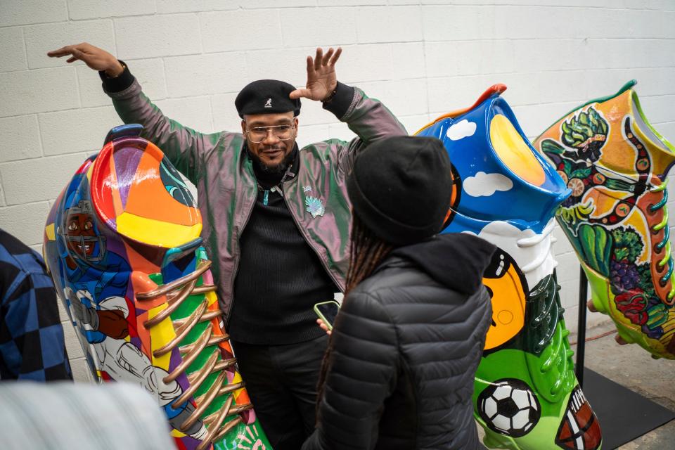Detroit artist Trae Isaac, left, speaks about his mural painted on an oversize cleat that will be one of the 20 local artist works in the DCLEATED exhibit, which was introduced during a media event at Huber Yard in Detroit on Thursday, March 21, 2024. The cleats highlight local charity organizations and will be scattered throughout downtown Detroit during the 2024 NFL draft, which is being held in Detroit.