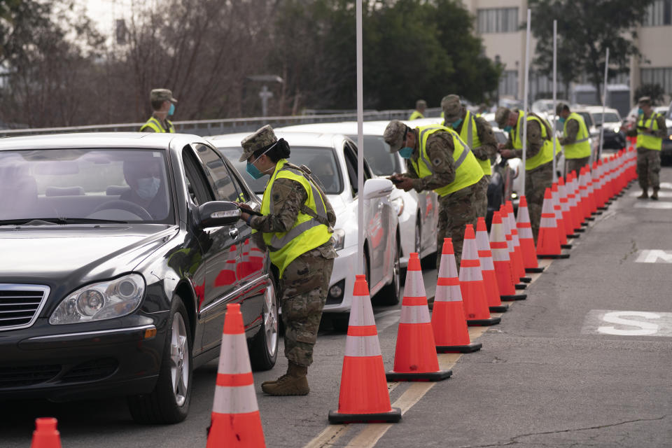 Members of the National Guard help motorists check in at a federally-run COVID-19 vaccination site set up on the campus of California State University of Los Angeles in Los Angeles, Tuesday, Feb. 16, 2021. (AP Photo/Jae C. Hong)