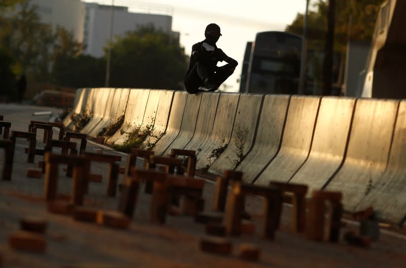 A student protester sits next to a roadblock outside the City University in Kowloon Tong, Hong Kong