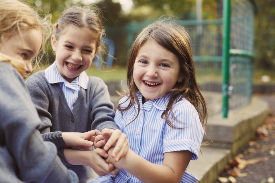 Elementary schoolgirls playing hand game in school playground