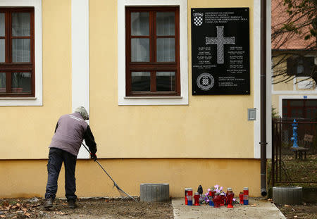 A man cleans a street next to a plaque containing a pro-nazi salute honoring Croatian fighters killed during the 1990s' war in Jasenovac, Croatia, February 8, 2017. REUTERS/Antonio Bronic