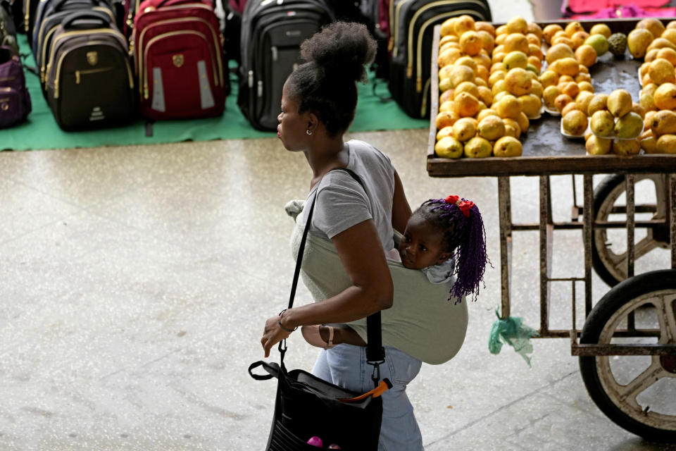 A commuter carries a child at the bus station the day after presidential elections lead to a second round in Brasilia, Brazil, Monday, Oct. 3, 2022. The second round is set for Oct. 30. (AP Photo/Eraldo Peres)