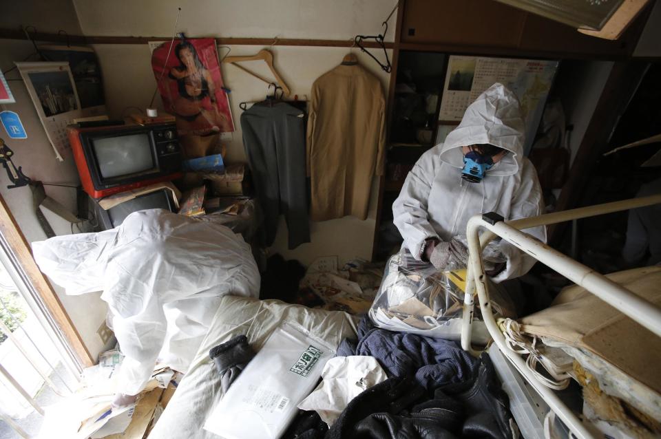 Los trabajadores ponen la basura en las bolsas de plástico en un piso vacío de Tokio tras la muerte del propietario.